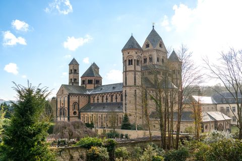 Eine beeindruckende Kirche mit mehreren Türmen und einem historischen Baustil. Die umgebende Landschaft ist grün und einladend.