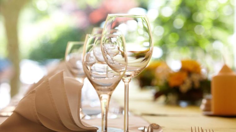 Ein eleganter Esstisch mit mehreren Gläsern und gefalteten Servietten. Die Umgebung ist hell und einladend.