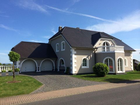 Ein schönes modernes Haus mit einem großen Garten. Die Fassade ist hell und die Garage hat Platz für zwei Fahrzeuge.