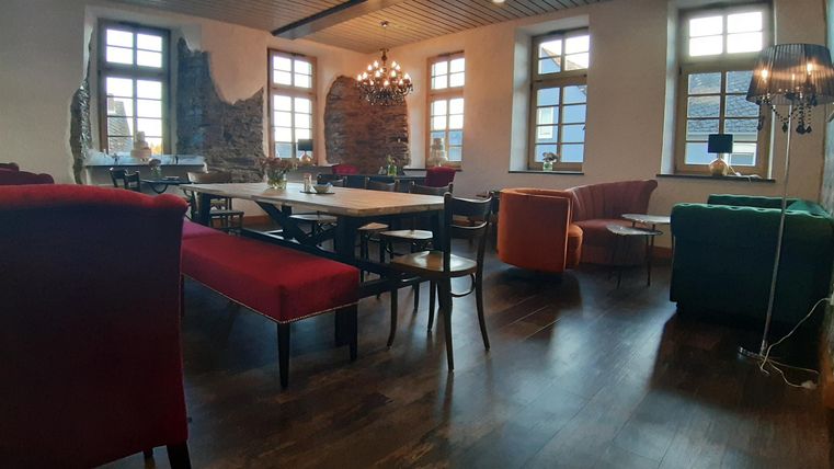 Ein stilvolles Café mit verschiedenen Sitzbereichen und großen Fenstern. Der Raum hat einen modernen, einladenden Look.